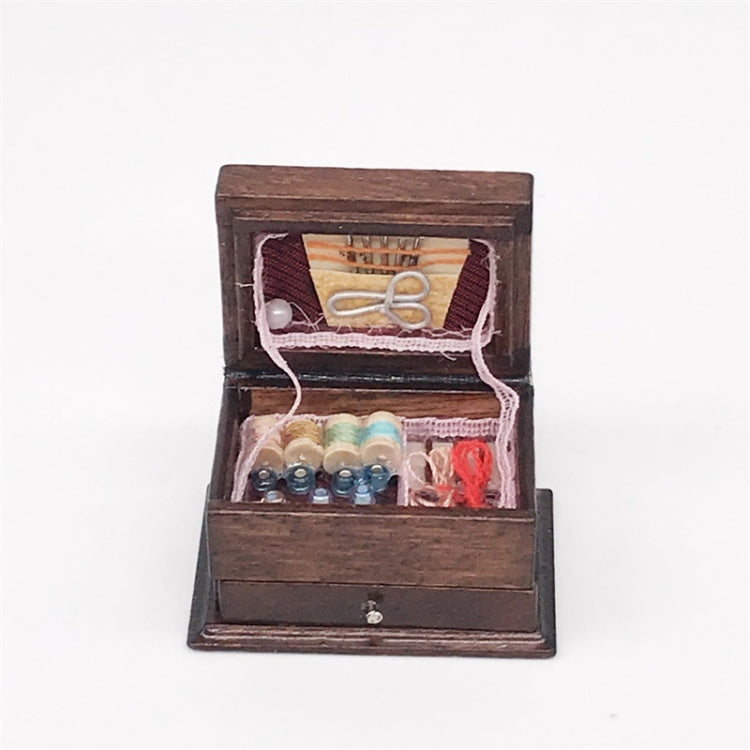 Mini wooden sewing box with open lid, thread spools, needles, and fabric trim inside
