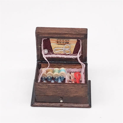 Mini wooden sewing box with open lid, thread spools, needles, and fabric trim inside