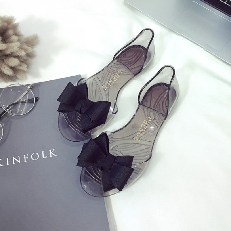 Transparent flat jelly shoes with black bow detail and slingback strap