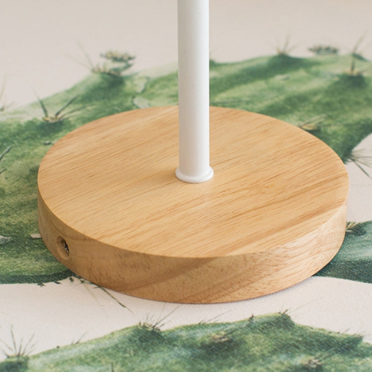 Round wooden base with vertical white post, on green patterned fabric
