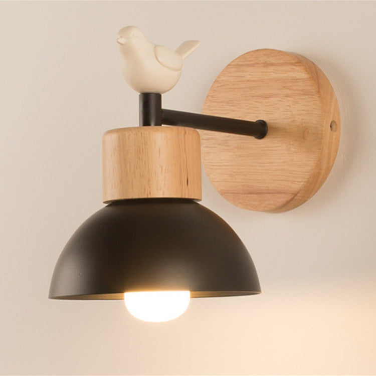 Wall lamp with ceramic bird topper, wood cylinder body, black shade, glowing bulb