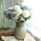 Simulated dandelion flower bouquet with pale green and blue ball blooms in a vase