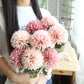 Simulated dandelion flower bouquet with blush and pink ball blooms and green leaves
