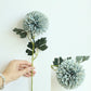 Simulated dandelion flower stem with light blue ball bloom and green leaves