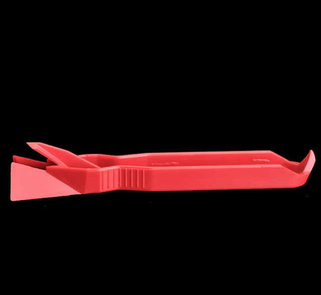 Red plastic floor scraper with wide blade and ribbed grip, adhesive removal tool