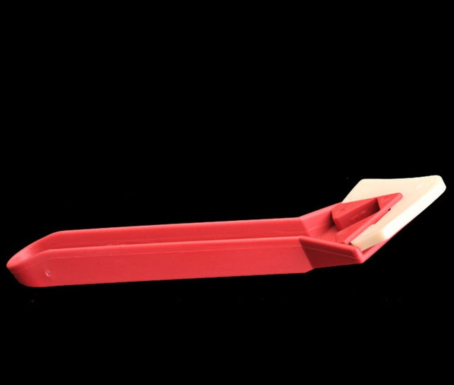 Red scraper tool with cream-colored blade insert, for removing adhesive residue
