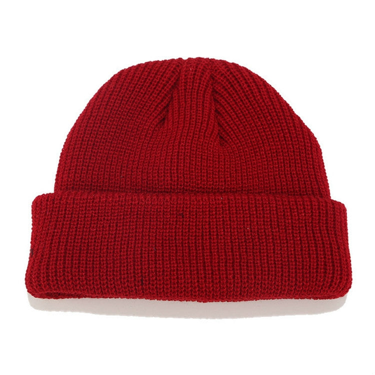 Red ribbed knit beanie with folded cuff and small top knot detail