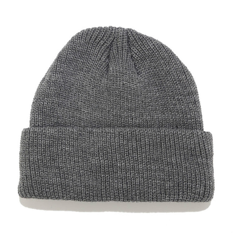 Dark gray ribbed knit beanie with folded cuff and small top knot detail