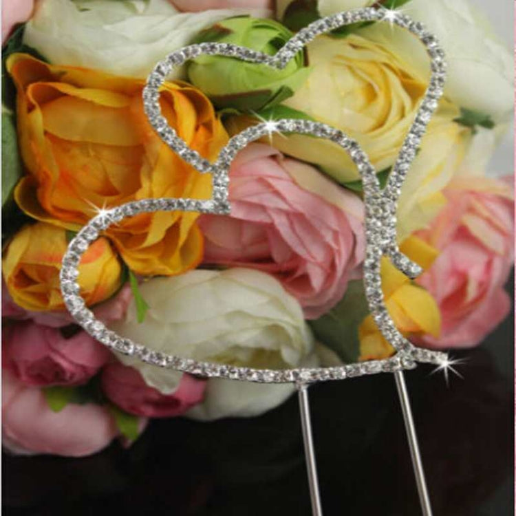 Crystal heart cake topper with two stacked hearts in front of rose bouquet
