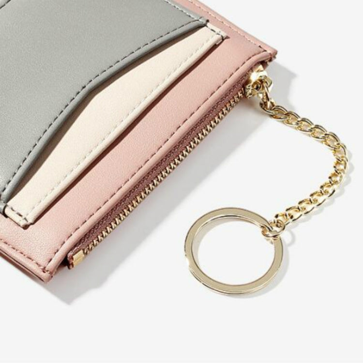 Close-up: pink mini wallet with gray fold, beige card slot, zipper, and gold chain