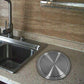 Stainless steel round trash can lid on countertop near a sink