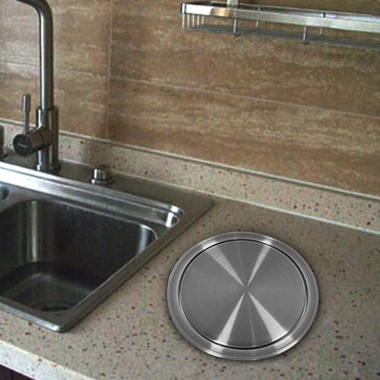 Stainless steel round trash can lid on countertop near a sink