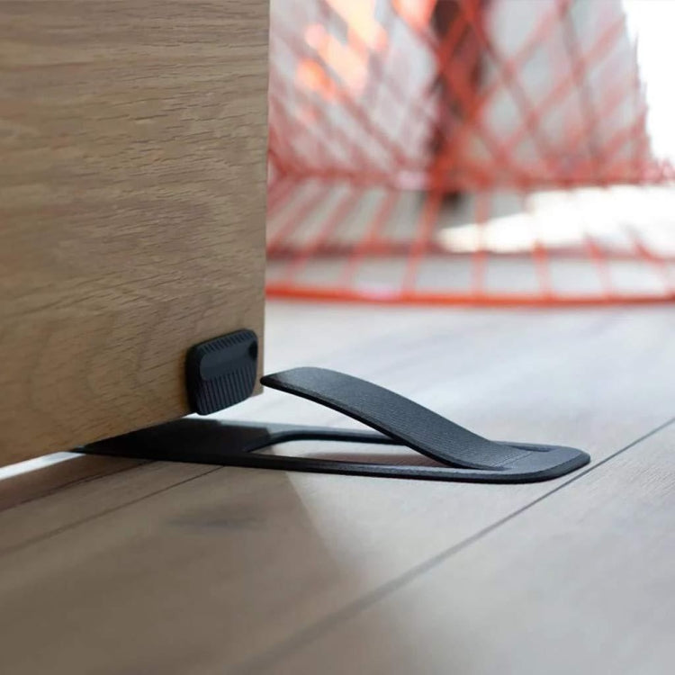 Black spring door stopper wedge securing a door at the floor