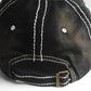 Black cap close-up: white contrast stitching and metal buckle on adjustable strap
