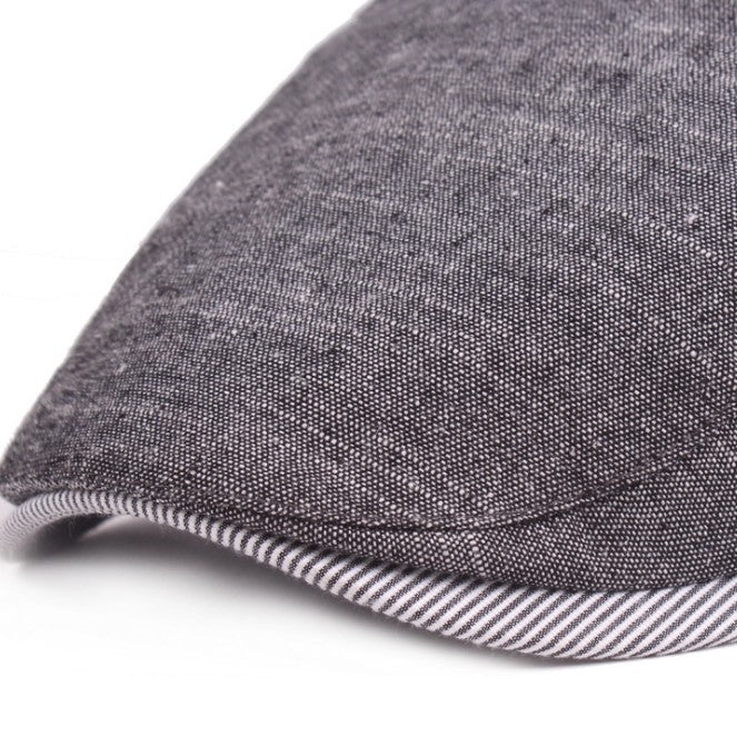Close-up of dark gray cotton-linen beret brim with striped edge trim