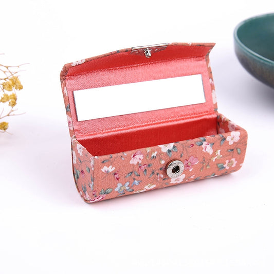 Peach floral portable makeup mirror case with open lid and red interior lining