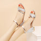 Pair of silver glitter heeled sandals with ankle buckle straps and open toe