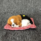 Plush sleeping dog ornament toy, brown and black with white paws, in red plaid bed