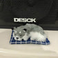 Plush sleeping dog ornament toy, gray and white fur, on blue plaid mat