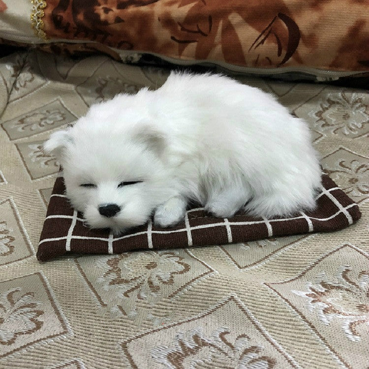 Plush sleeping dog ornament toy, white fur, on dark plaid cushion