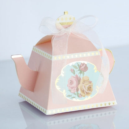 Pink teapot-shaped candy box with floral medallion, ribbon handle, and gift wrap bow