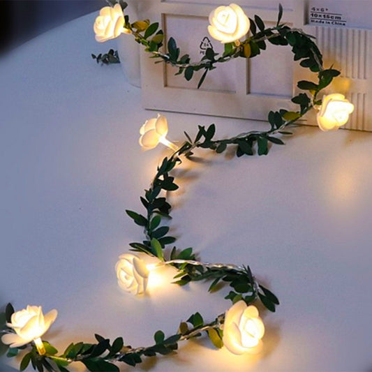 Rose-flower LED light string garland with green leaf vine, warm glowing bulbs