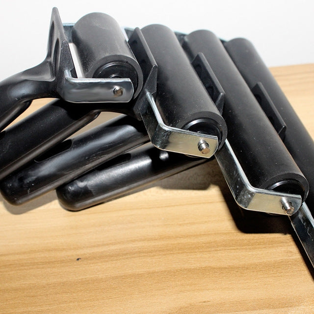 Close-up of black rubber roller printing tools with metal axles and brackets
