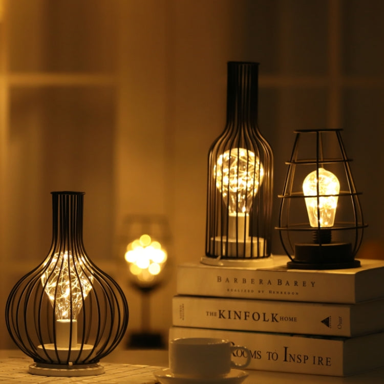 Bottle-shaped LED table lamp and wire cage LED lamp glowing on a side table