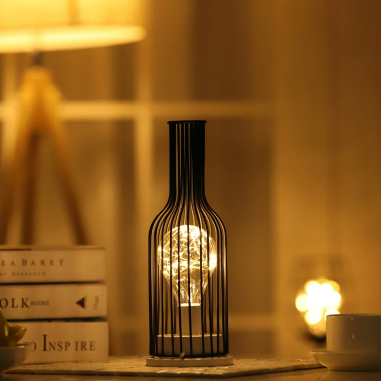 Bottle-shaped LED table lamp with warm glowing light on a tabletop