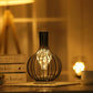 Bottle-shaped LED table lamp with black iron cage, warm glowing bulb
