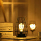 LED table lamp with black geometric iron cage and warm glowing bulb