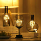 Three metal-caged LED table lamps with bottle silhouettes, warm ambient glow