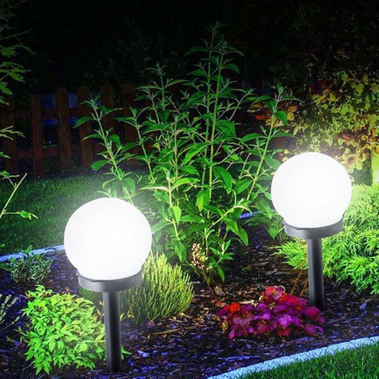 Solar ground bulb lights with round white glass heads, two-piece set, glowing in yard