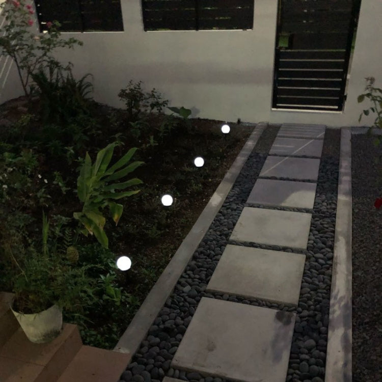 Solar ground pathway lights with round glowing heads along a garden walkway