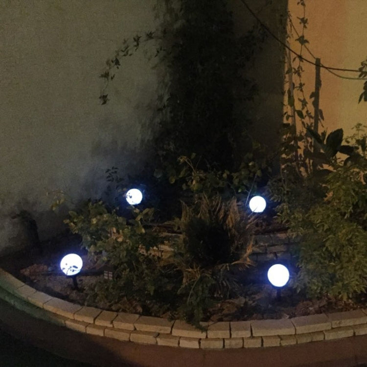 Solar garden ground lights with round white heads glowing along a curved bed