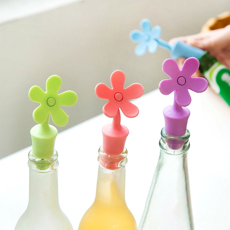 Set of colorful flower-shaped silicone bottle stoppers on bottles: green, red, purple, blue
