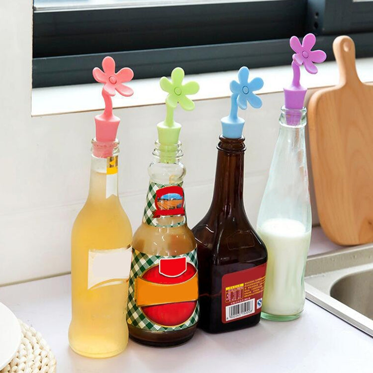 Colorful flower-shaped silicone bottle stoppers on wine bottles in a row