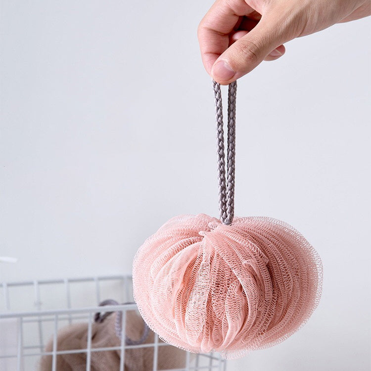 Pink mesh bath sponge lantern held by rope, round poof design