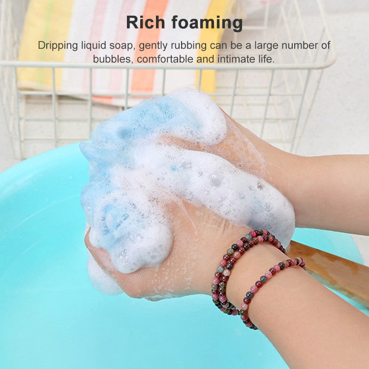 Blue soft mesh shower brush with wooden handle lathering on skin, hanging loop visible.