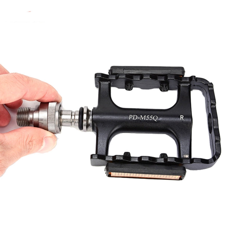 Hand pulling a quick-release axle from a black bike pedal with orange reflector strip