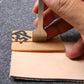 Hand using metal leather stitch punch tool to mark stitches on leather