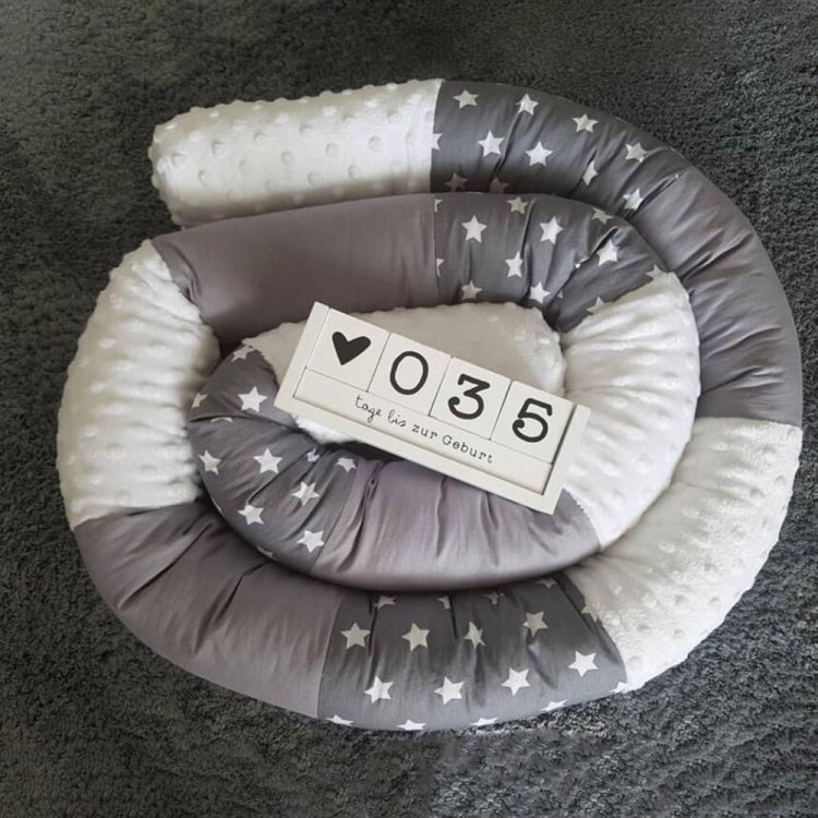 Cylindrical crib bumper nest in gray with star print and padded edges