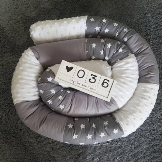 Cylindrical crib bumper nest in gray with star print and padded edges