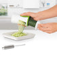 Person grating cucumber with white and green spiral grater over a tray, brush included.