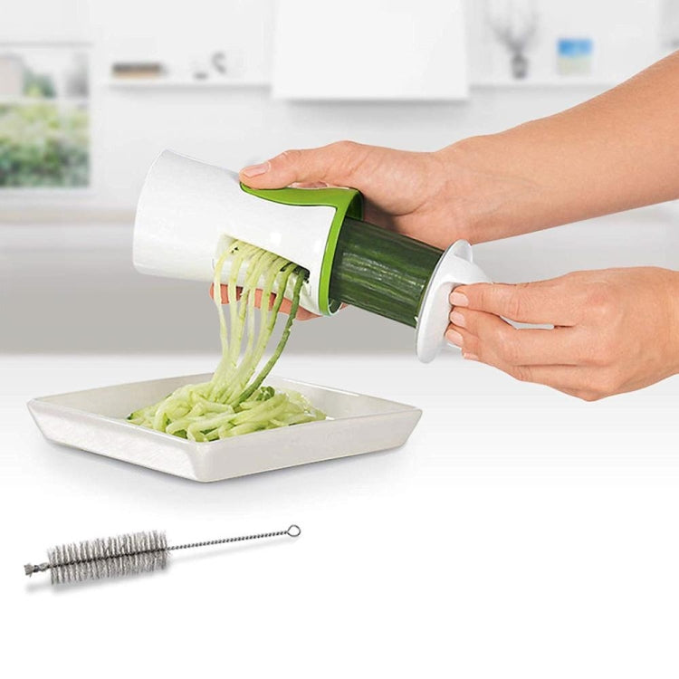 Person grating cucumber with white and green spiral grater over a tray, brush included.