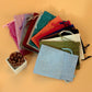 Assorted linen drawstring gift bags in pink, teal, green, and beige tones.