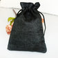 Black linen drawstring gift bag with gathered top and black rope tie.