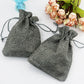 Gray linen drawstring gift bags, two pouches with braided rope ties.