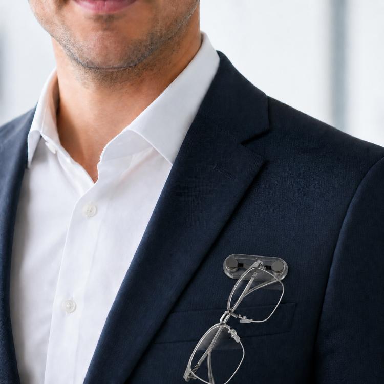 Magnetic glasses holder brooch clipped to a navy blazer lapel with eyeglasses