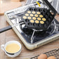 Non-stick egg puff maker on a countertop grill base with empty cavity wells